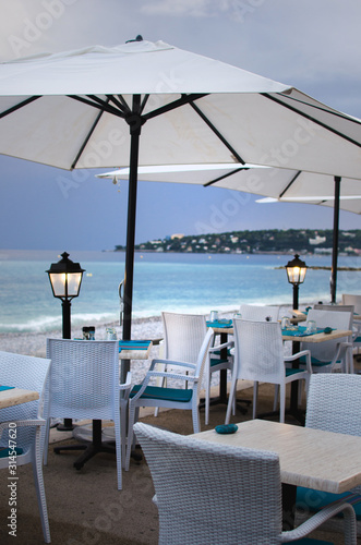 Tables for a romantic meal on the beach with lanterns and chairs. With sunset view. Menton  France