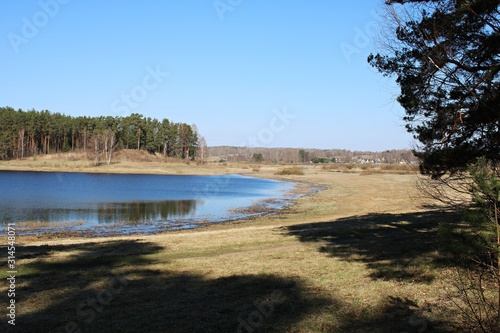 Fields, mixed forests and a beautiful lake on a cloudless, sunny day in the Pskov region of Russia. April 2019