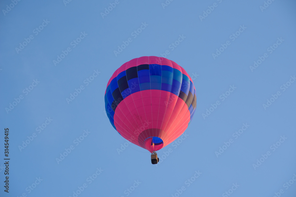Obraz premium Red and blue hot air balloon seen from below against blue sky