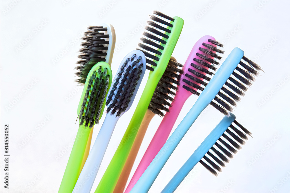 multi-colored toothbrushes with black bristles on a white background.