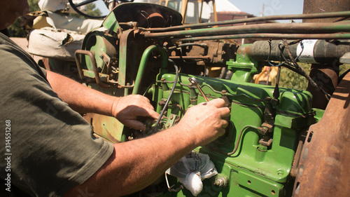 Close up of agricultural mechanic working on an antique farm tractor 