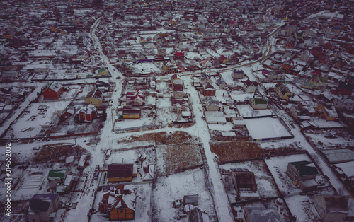 Top view at empty village. Snow covered roofs of houses, roads and courtyards. Flight above houses and cottages covered by.