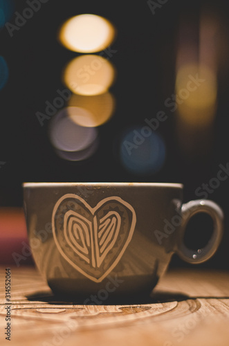 Heart cup with almond cappuccino and bokeh lights