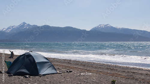 Tent on the beach on a sunny day at high tide with Kachemak Bay and Mountains - Alaska