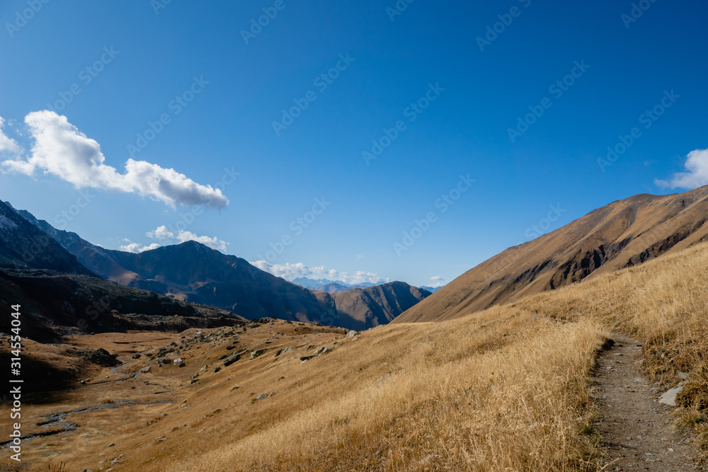 Juta trekking path landscape with river and mountains in sunny autumn day -  popular trekking  in the Caucasus mountains, Kazbegi region, Georgia.