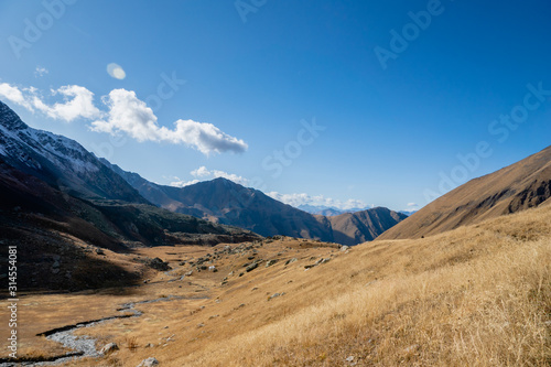 Juta trekking path landscape with river and mountains in sunny autumn day - popular trekking in the Caucasus mountains, Kazbegi region, Georgia.