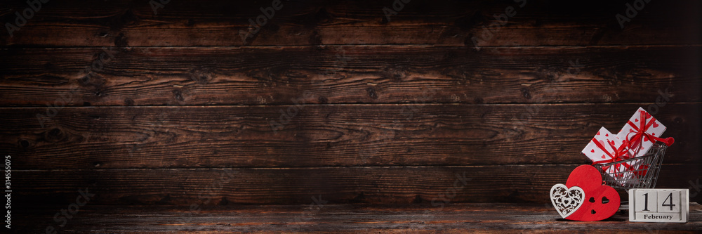 Shopping trolley, gifts, hearts on brown wooden background. 14 February. Valentine's Day. Extra wide panorama banner background Shopping trolley, gifts, hearts on brown wooden background. 14 February. Valentine's Day. Extra wide panorama banner background
