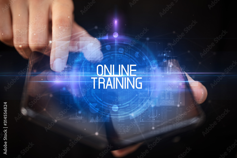 Young man holding a foldable smartphone with ONLINE TRAINING inscription, educational concept Young man holding a foldable smartphone with ONLINE TRAINING inscription, educational concept