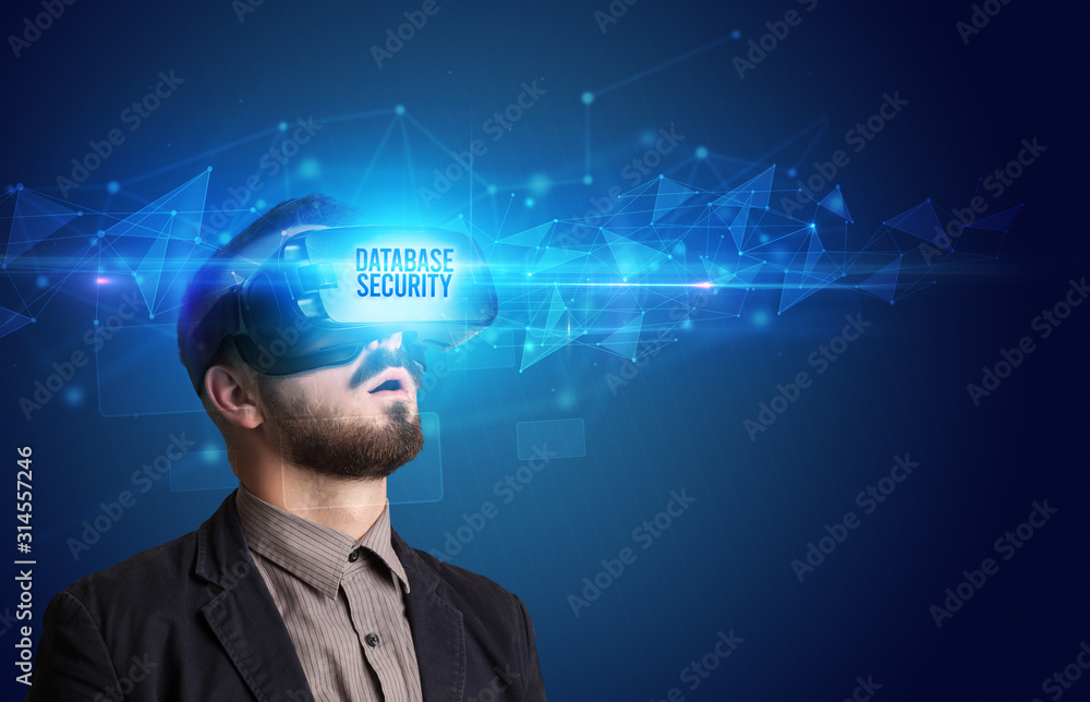 Businessman looking through Virtual Reality glasses with DATABASE SECURITY inscription, cyber security concept Businessman looking through Virtual Reality glasses with DATABASE SECURITY inscription, cyber security concept