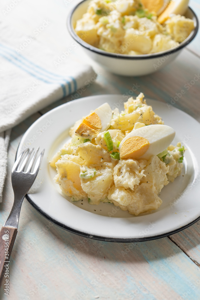 Potato salad with egg and mayonnaise on wooden background