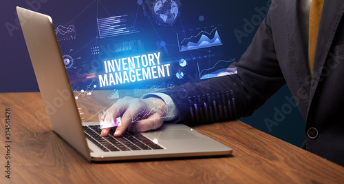 Businessman working on laptop with INVENTORY MANAGEMENT inscription, new business concept