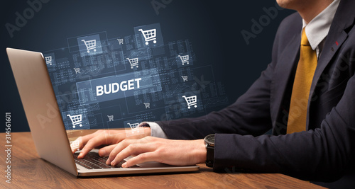 Businessman working on laptop with BUDGET inscription, online shopping concept