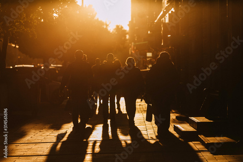 people walk along the street in the sunset