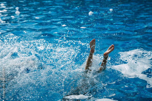 A girl jumps from a diving platform into the pool