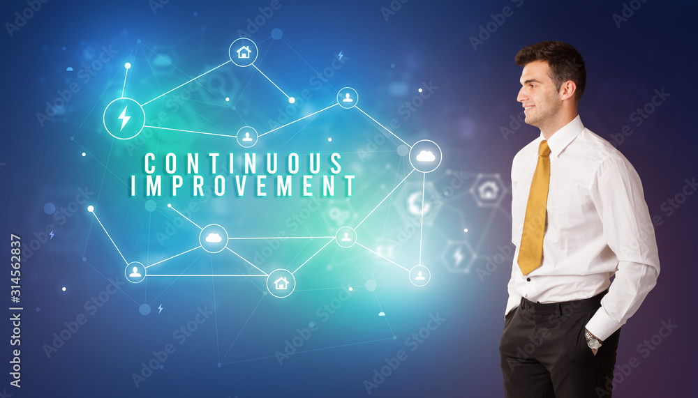 Businessman in front of cloud service icons with CONTINUOUS IMPROVEMENT inscription, modern technology concept Businessman in front of cloud service icons with CONTINUOUS IMPROVEMENT inscription, modern technology concept
