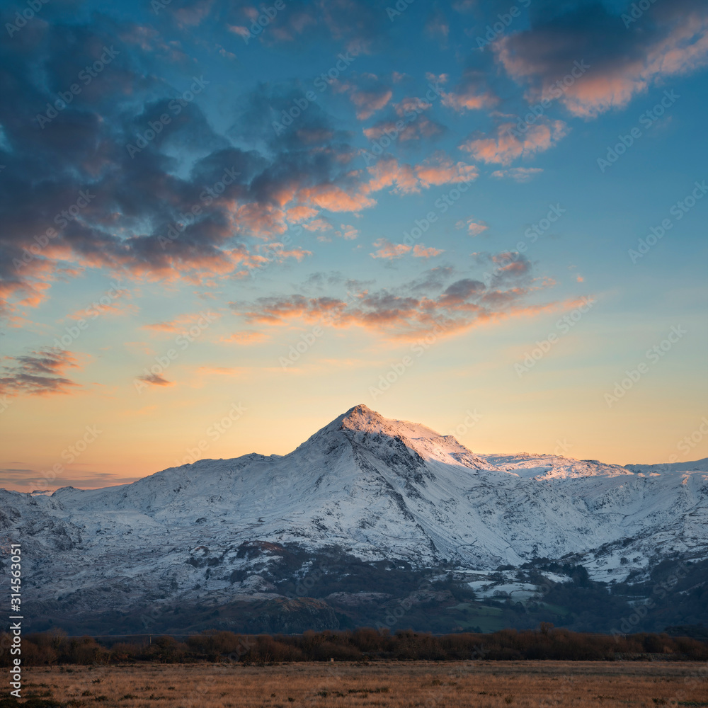 Eic landscape image of Snowdonia snowcapped mountains with dramatic sunset clouds and beautiful vibrant glow