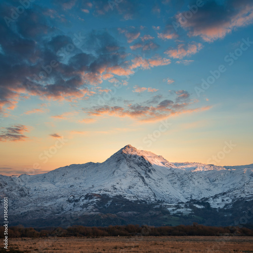 Obraz na płótnie Eic landscape image of Snowdonia snowcapped mountains with dramatic sunset cloud
