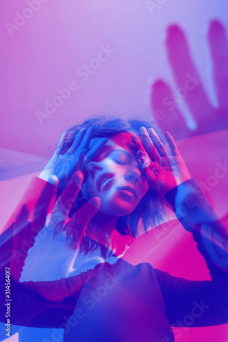 Emotional portrait. Young beautiful woman closing her face with hand. Color double exposure.