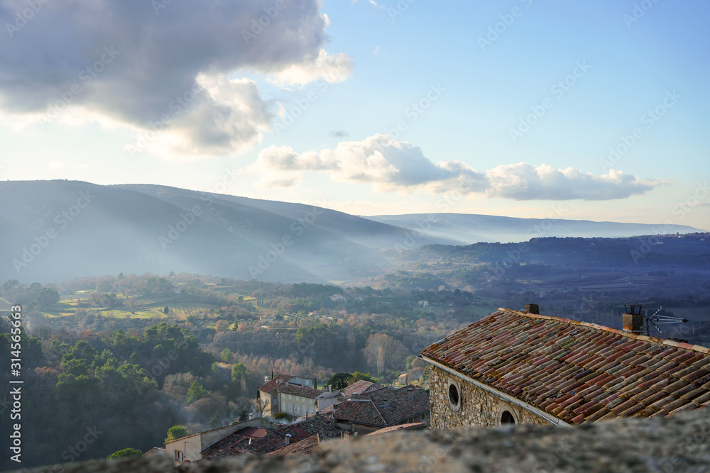 Vue depuis le village de Bonnieux sur le massif de Luberon, brume, ciel bleu nuageux.
