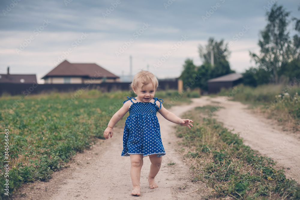 small child in sundress on summer village road small child in sundress on summer village road