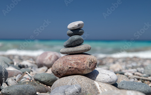 Gravel / pebble beach at the southwest coast of Rhodes island near Apolakkia with multi colored ocean water and small stone figures