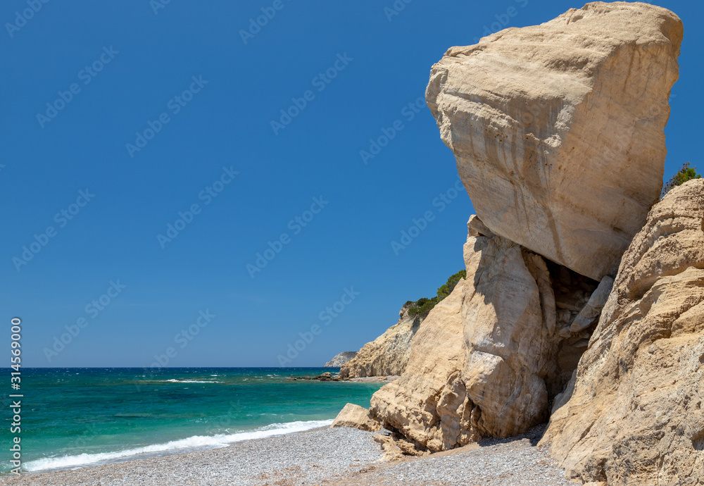 Fototapeta premium Gravel / pebble beach Akra Fourni nearby Monolithos at Rhodes island with multi colored ocean water and rock formation