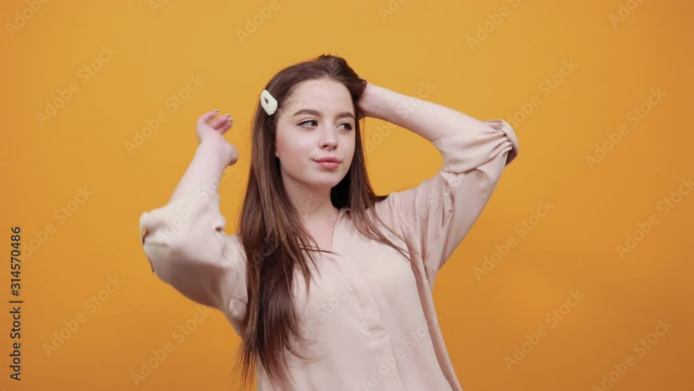 Cheerful caucasian brunette woman in fashion pastel shirt keeping hands on neck, stretched muscules, relax isolated on orange background in studio. People sincere emotions, lifestyle concept. Cheerful caucasian brunette woman in fashion pastel shirt keeping hands on neck, stretched muscules, relax isolated on orange background in studio. People sincere emotions, lifestyle concept.