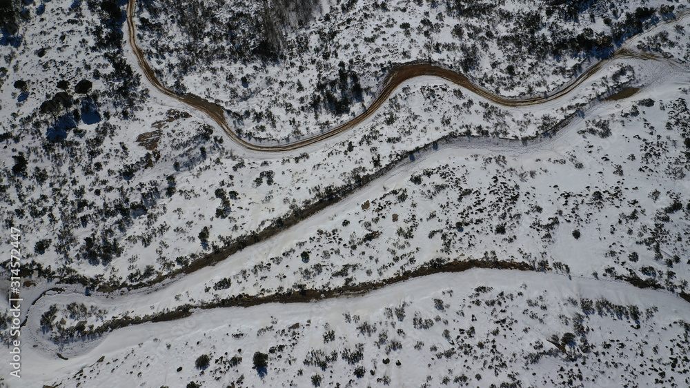 Aerial drone view of curvy road in beautiful snowed mountain in winter