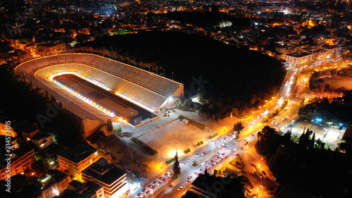 Aerial drone night shot of beautiful illuminated Panathenaic stadium in cityscape of Athens, Attica, Greece