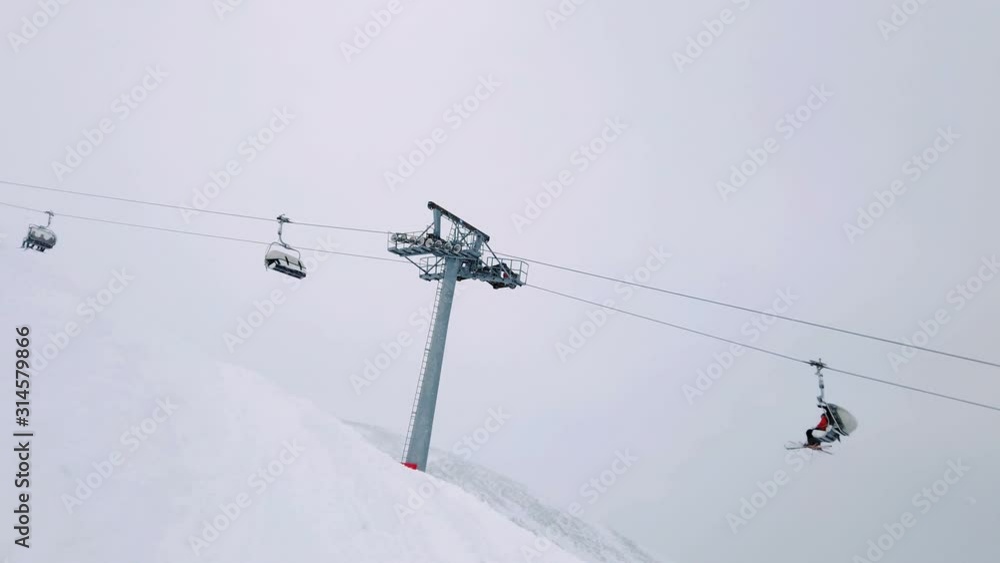 Moving ski chair lift station on mountain top in cloudy winter day Moving ski chair lift station on mountain top in cloudy winter day