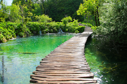 Fototapet Wooden footbridge built above the blue waters of the Plitvice Lakes National Par