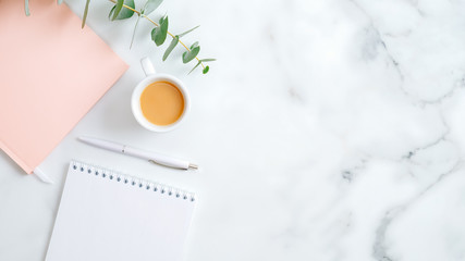 Wedding planner, cup of coffee, pink notebook, pen, eucalyptus leaf on marble desk. Flat lay, top view, copy space. Wedding, bridal, marriage concept.