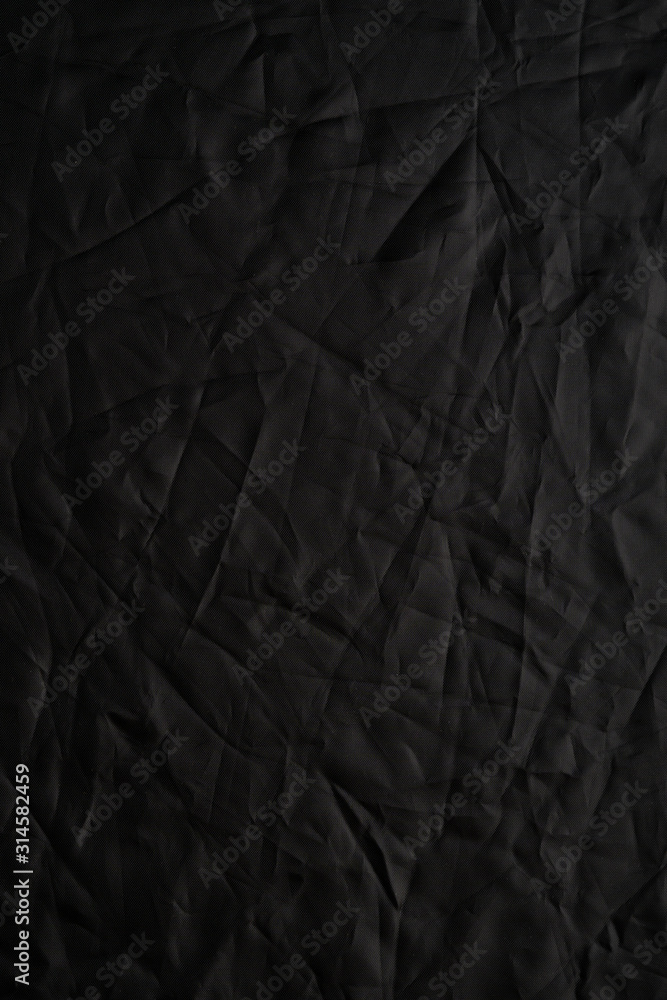 Fototapeta premium Texture of crumpled black fabric with a blue tint. Creative vintage background. Black flag.