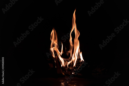 Close-up of beautiful orange-red flames in the fireplace in the center in the dark