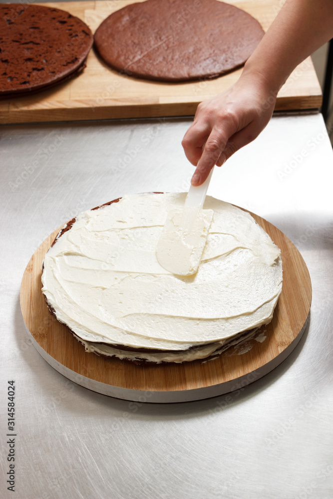 Woman is preparing chocolate cake with milk cream. The process of making the chocolate cake, from begin to the end. Made by hands for confectionery. Woman is preparing chocolate cake with milk cream. The process of making the chocolate cake, from begin to the end. Made by hands for confectionery.
