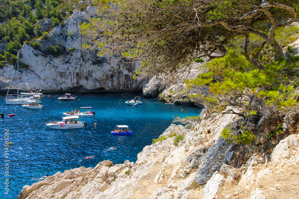 Beautiful cove of Sugiton near Marseille in the South of France - Boats filled with holidaymakers enjoying the turquoise waters of the Calanques de Marseille National Park