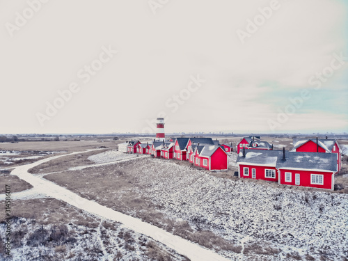 Scenic view of colorful wooden buildings top view. Fishing village and tourist town. Wooden red houses of fishing village in snowy covered in winter. A few red houses near the lighthouse on the hill. photo