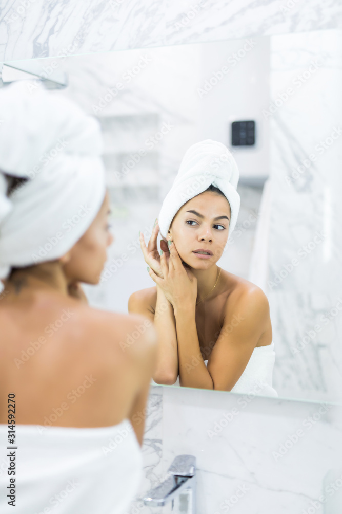 Face of young beautiful healthy woman and reflection in the mirror in bathroom Face of young beautiful healthy woman and reflection in the mirror in bathroom