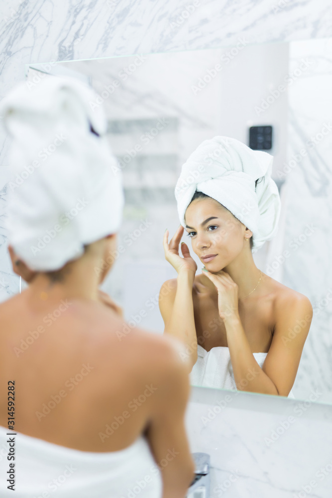 Face of young beautiful healthy woman and reflection in the mirror in bathroom Face of young beautiful healthy woman and reflection in the mirror in bathroom