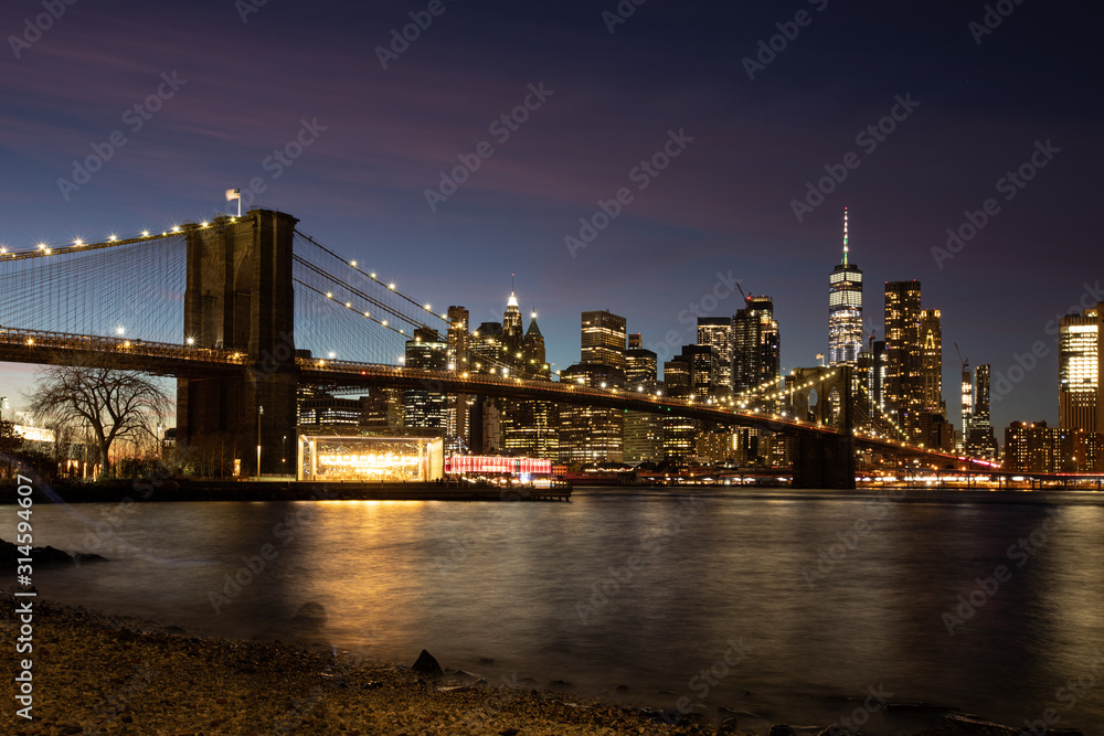 NYC skyline including Brooklyn Bridge during a colorful dusk. 