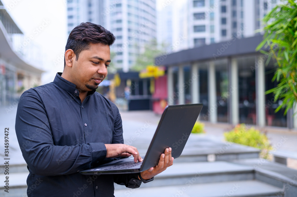 Young entrepreneur or Businessman working on laptop outside the office building. Young entrepreneur or Businessman working on laptop outside the office building.