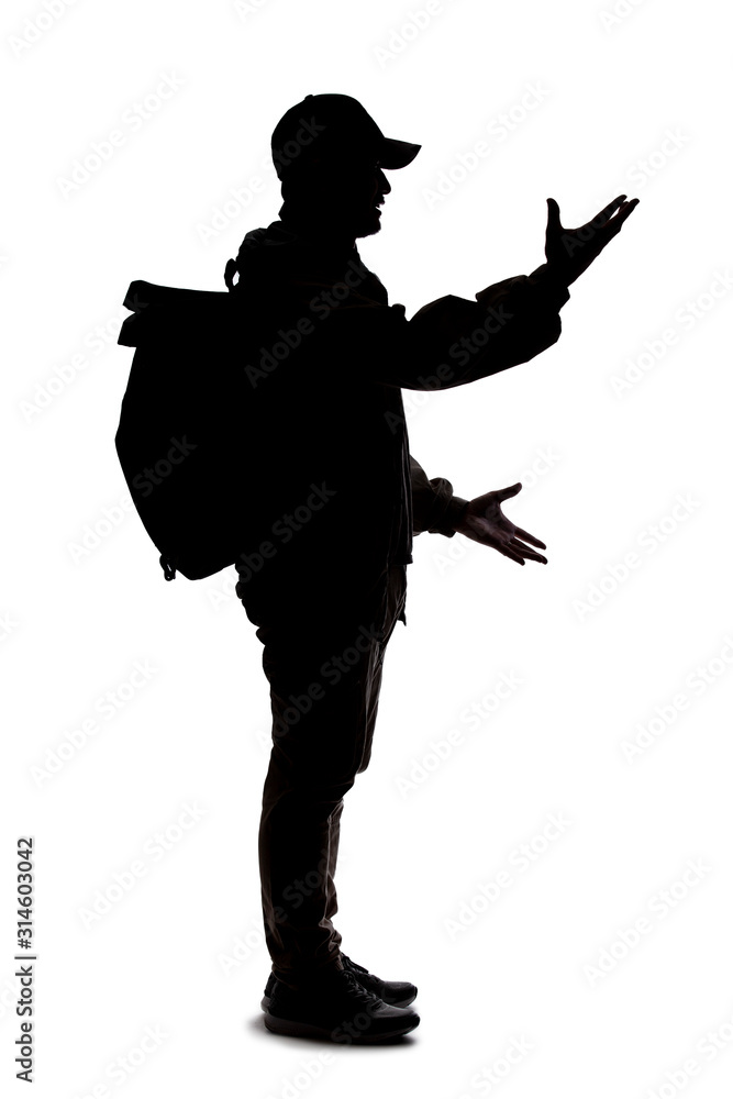 Naklejka Silhouette of a man wearing a backpack looking like a traveler or hiker trekking. He is gesturing like he is talking or speaking
