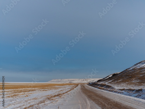 winter country road in the snow covered steppe and clear blue sk