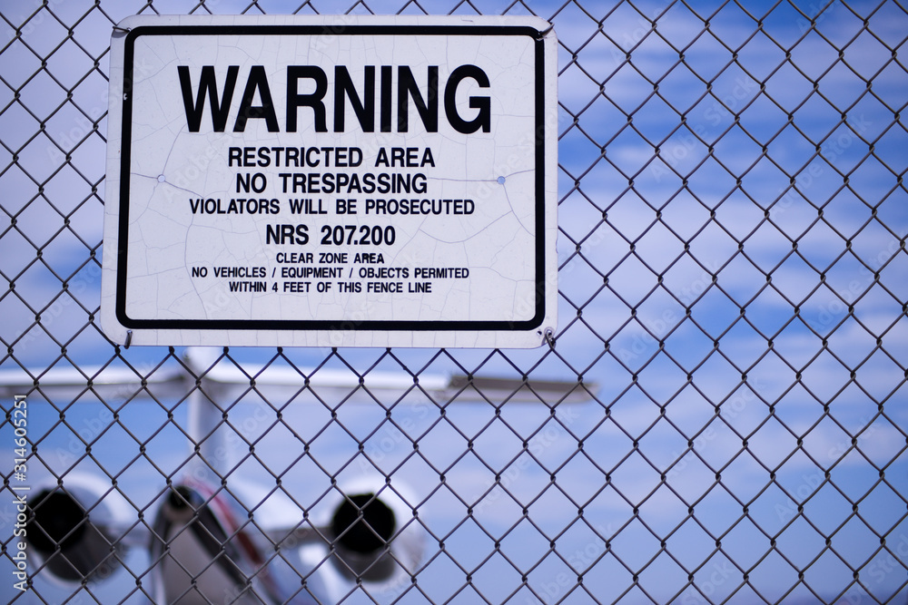 Personal Jet behind Airport Fence Warning Sign