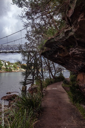 edge cliff surrounding the beach with boat harbor and a beautiful bridge in the background.