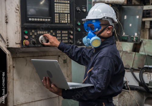 Chemical engineers wear helmet hat, and put chemical-resistant masks, carry laptops, inspect and control chemicals in the factory.