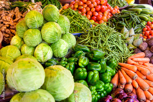 Abundance of vegetables in Asian street market. Heaps of various vegetables at bazaar in India  close up. Cabbage  carrots  eggplant  tomatoes  green paprika string beans.