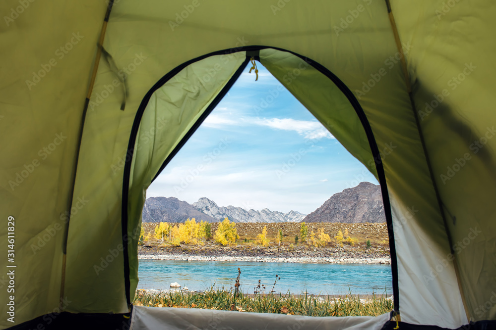 View from the tourist tent on beautiful landscape with turquoise river and high mountains under blue sky. Camping at mountain. Inside the green tent, copy space.