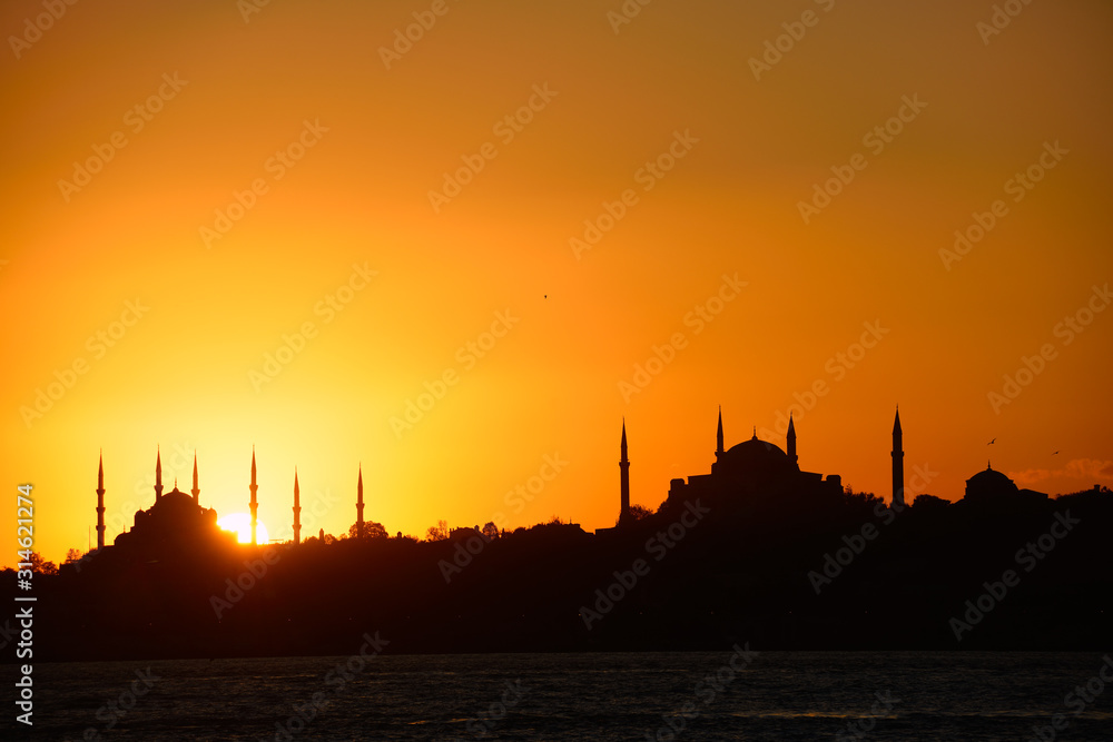 Sun setting behind Blue Mosque with Hagia Sophia in silhouette on the Bosphorus Istanbul