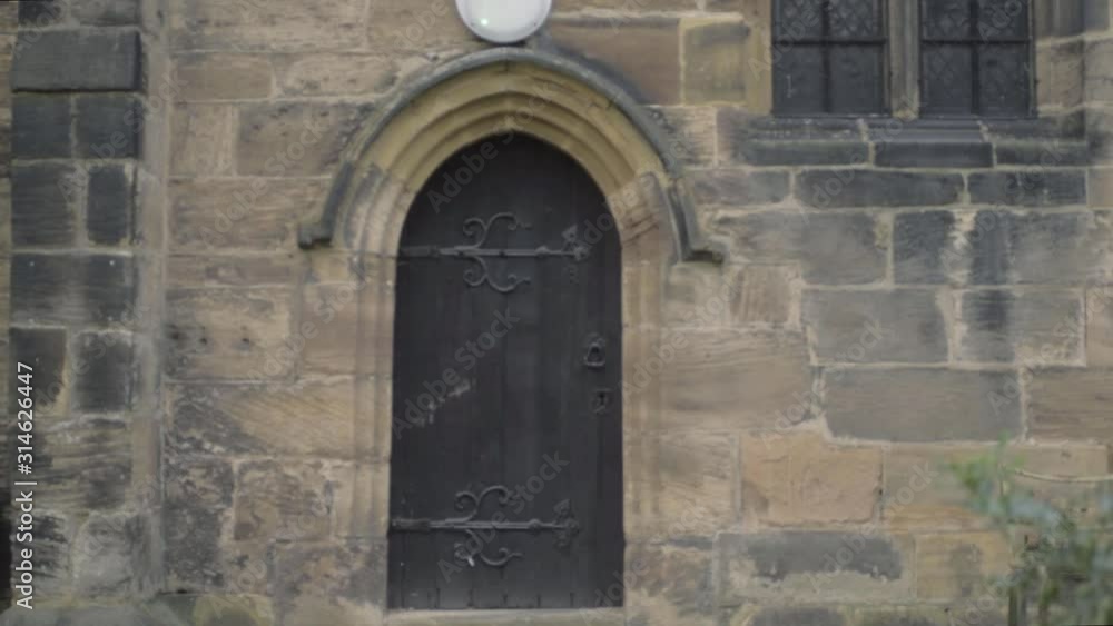 Gothic looking old black wooden door in stone church building wide panning Gothic looking old black wooden door in stone church building wide panning